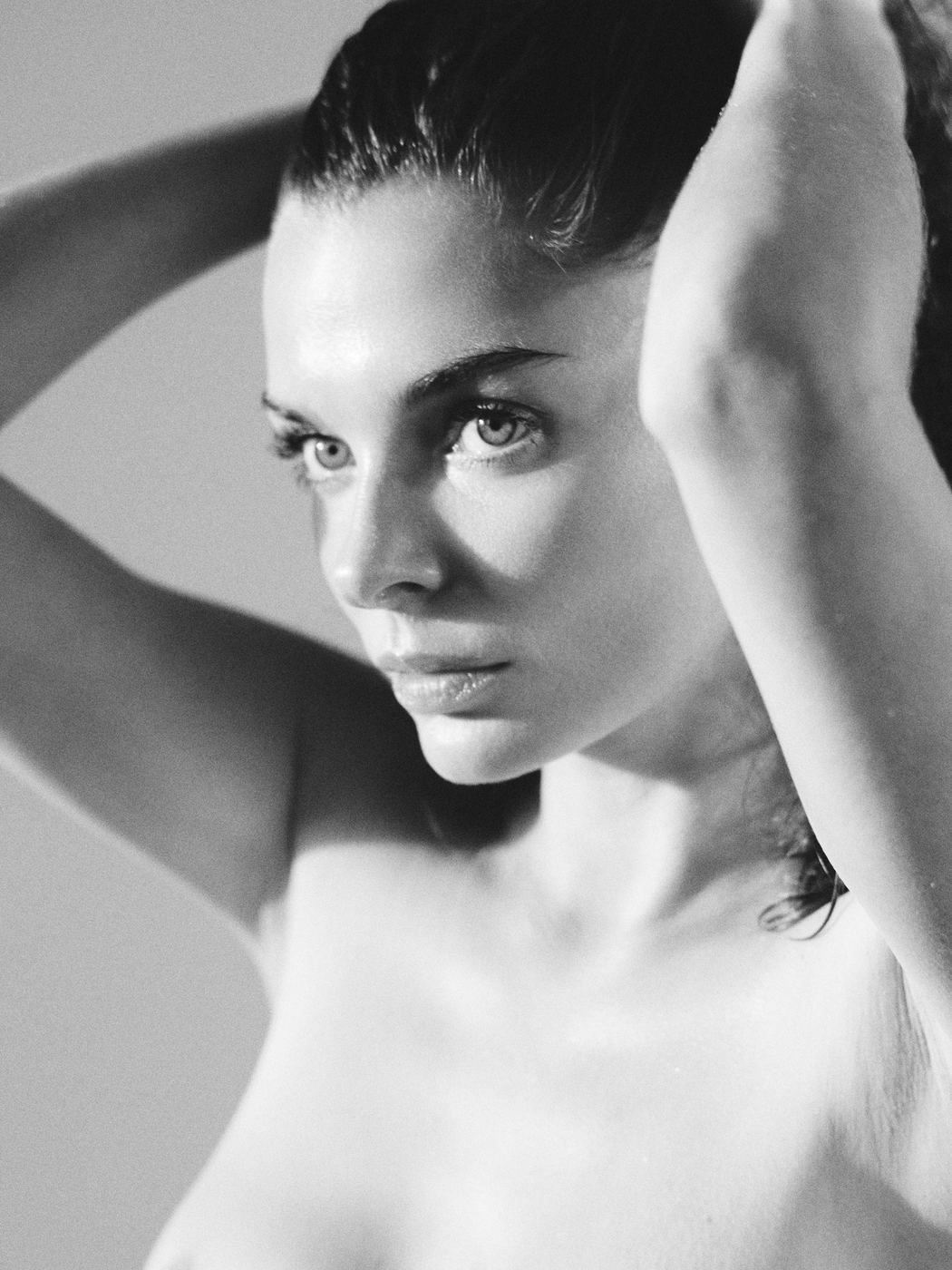 Beauty portrait of a woman with arms raised over her head, natural light, black and white, by Armand Sanchez