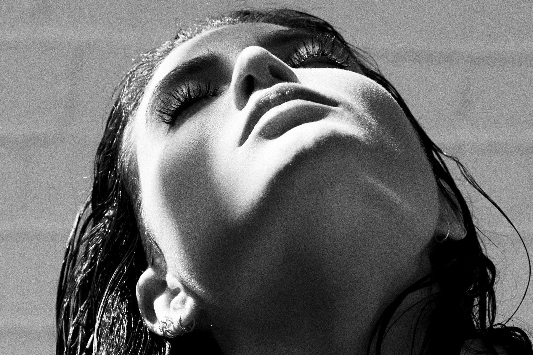 Fine art portrait of a woman with wet hair looking upward, dramatic black and white photograph by ARMAND