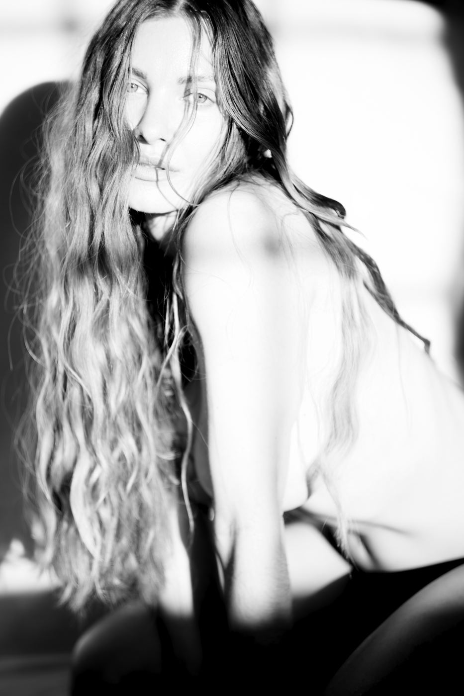 Editorial window-light portrait of a woman with long hair, black and white, by Armand Sanchez