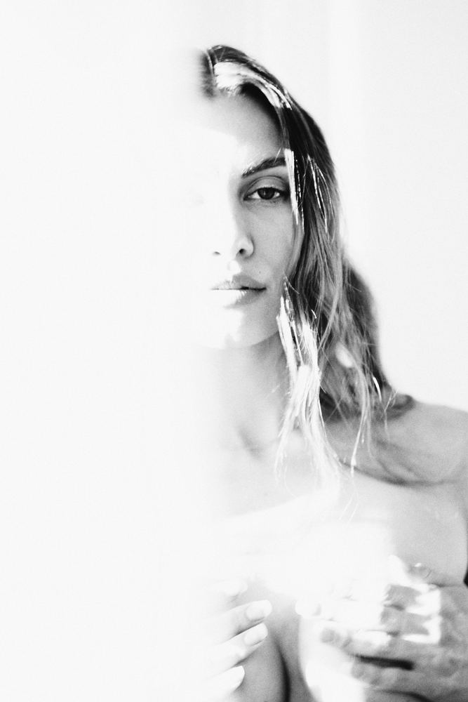 Editorial photograph of a woman with wet hair in bright high-key light, black and white