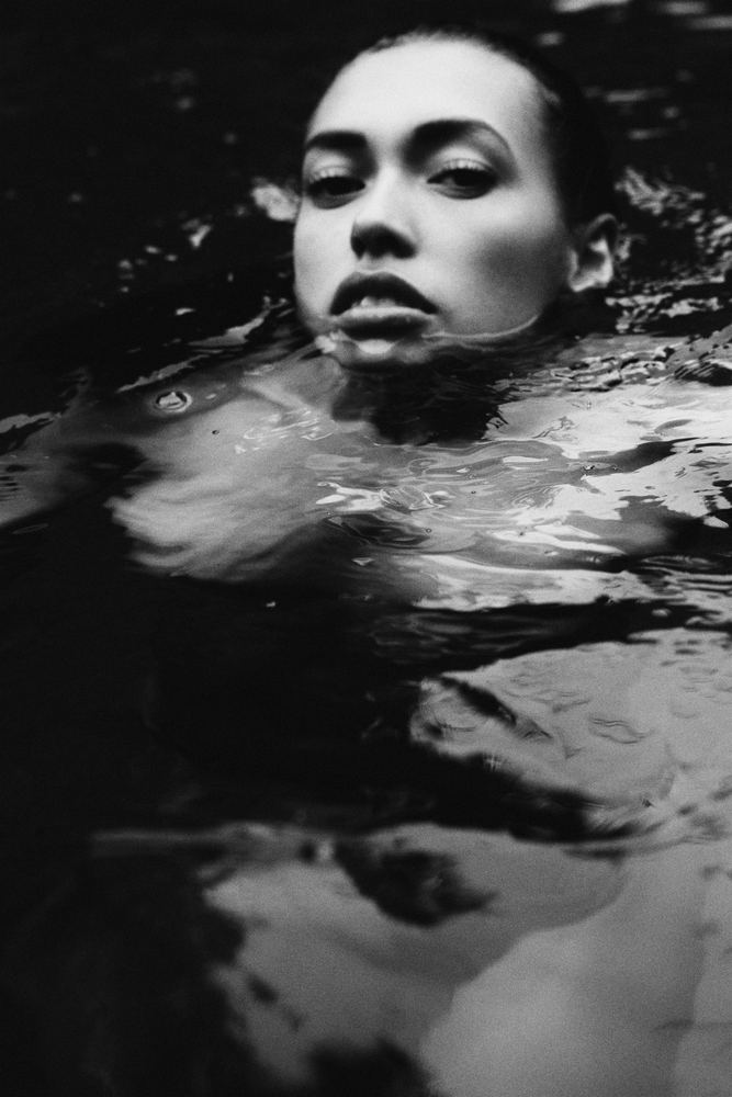 Fine art photograph of a woman submerged in dark water, black and white
