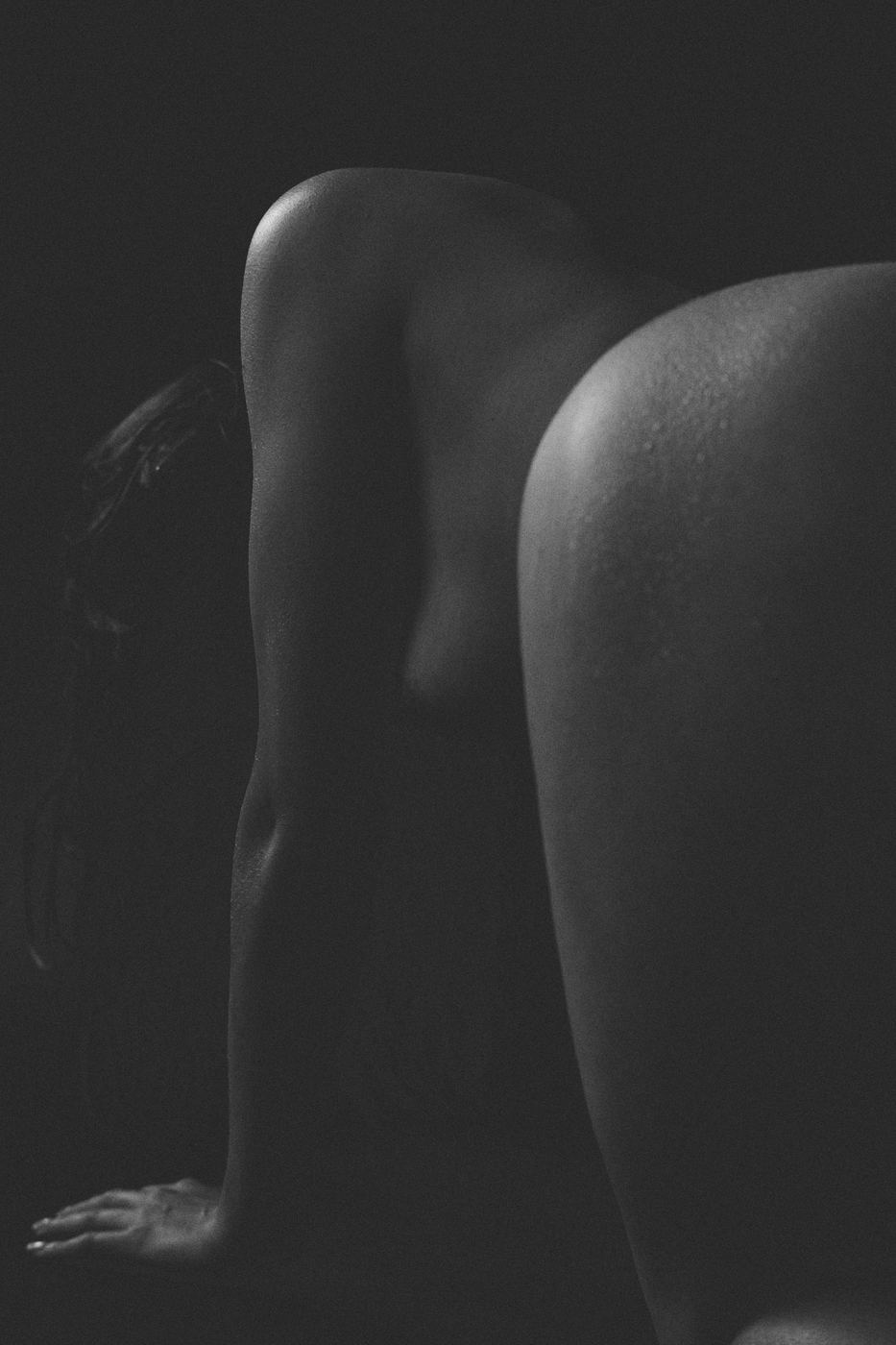 Low-key fine art nude study of a back in shadow, black and white